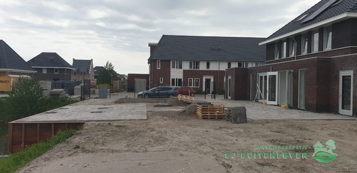 Tuinaanleg in Spanbroek, overzicht op afstand met cortenstalen oeverrand langs de sloot en terras in aanleg.