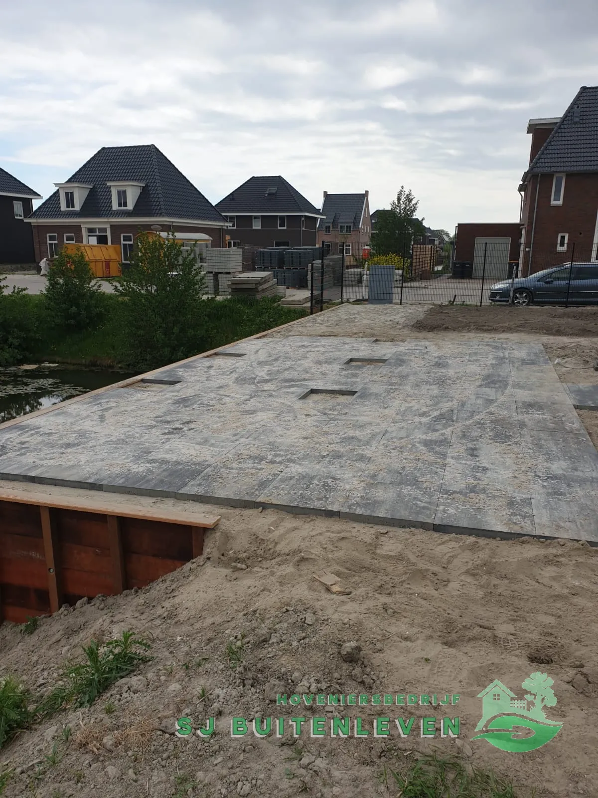 Bestraat terras met cortenstalen oeverrand en uitsparingen in de tegels voor beplanting, tuinaanleg in Spanbroek.